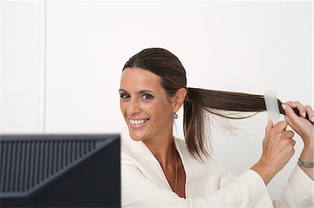 Mature businesswoman brushing hair at desk Stock Photo - Premium Royalty-Free, Code: 632-06779194