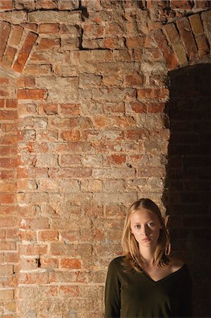simsearch:632-06779169,k - Young woman in front of brick wall, portrait Photographie de stock - Premium Libres de Droits, Code: 632-06779213
