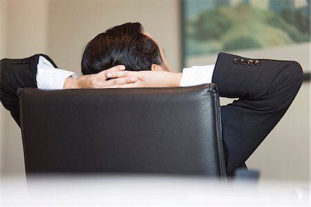 simsearch:632-06118255,k - Business executive relaxing in office chair with hands behind head Photographie de stock - Premium Libres de Droits, Code: 632-06779335