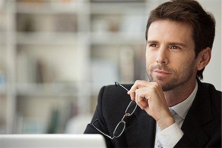 Businessman looking away in thought, glasses in hand Stock Photo - Premium Royalty-Free, Code: 632-06967592