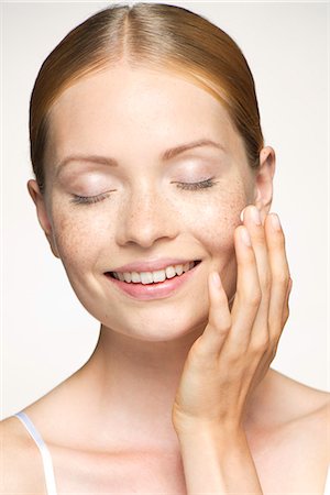 Young woman moisturizing face, eyes closed Stock Photo - Premium Royalty-Free, Code: 632-07494936