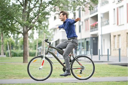 side view of a guy riding a bike - Man riding bicycle with arms outstretched Stock Photo - Premium Royalty-Free, Code: 632-07494983