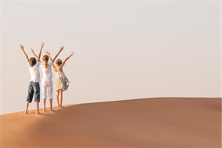 preteen girls in the sand - Children standing in desert with arms raised in air Photographie de stock - Premium Libres de Droits, Code: 632-07495022