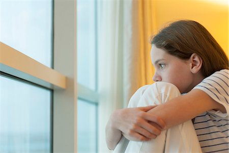 Preteen girl hugging knees, looking out window Stock Photo - Premium Royalty-Free, Code: 632-07495031
