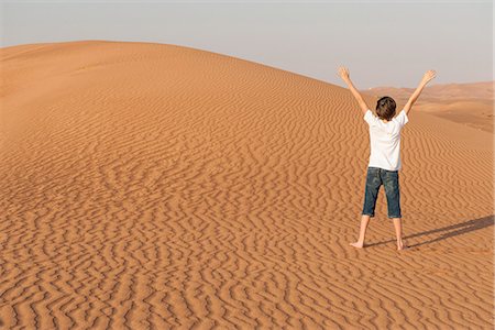 Teenage boy standing in desert with arms raised, rear view Photographie de stock - Premium Libres de Droits, Code: 632-07495043