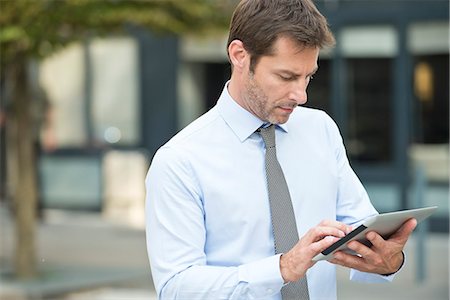 social media connection - Businessman using digital tablet outdoors Stock Photo - Premium Royalty-Free, Code: 632-07495078