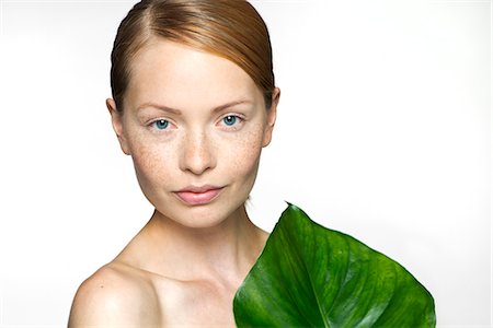 Young woman with tropical plant leaf, portrait Stock Photo - Premium Royalty-Free, Code: 632-07539991