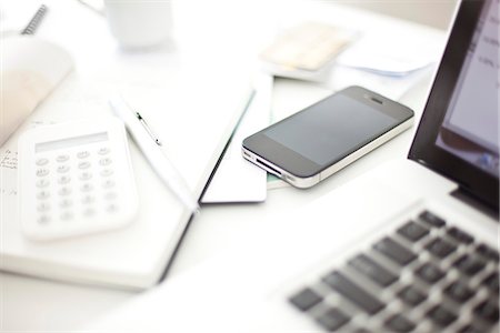 Smartphone resting on desk in in home office Stock Photo - Premium Royalty-Free, Code: 632-07540036