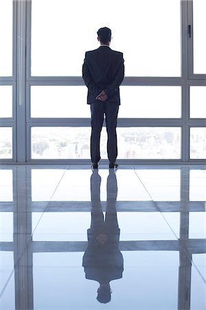 silhouette man not illustration not white background not cutout not couple not friends not family not black background - Businessman looking out high rise window at view of city below at sunset Stock Photo - Premium Royalty-Free, Code: 632-07674449