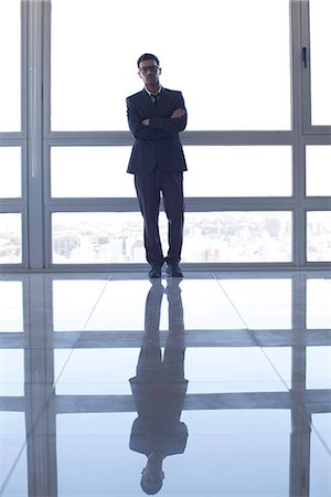 Businessman learning against high rise window, backlit by sunset glow Stock Photo - Premium Royalty-Free, Code: 632-07674450