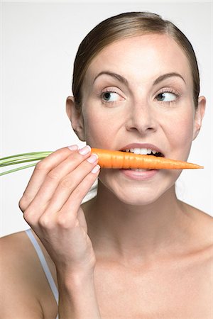 simsearch:632-07674608,k - Young woman biting into carrot Photographie de stock - Premium Libres de Droits, Code: 632-07674469