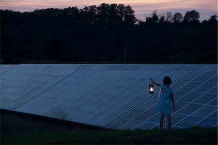 Girl standing in front of solar panels at twilight with old-fashioned lantern in hand Stock Photo - Premium Royalty-Free, Code: 632-07674477