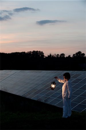 pyjamas (sleepwear with pants) - Girl standing in front of solar panels at twilight with old-fashioned lantern in hand Stock Photo - Premium Royalty-Free, Code: 632-07674478