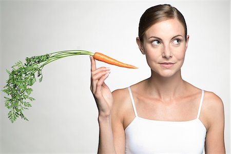 simsearch:632-06317597,k - Young woman holding up raw carrot Fotografie stock - Premium Royalty-Free, Codice: 632-07674471