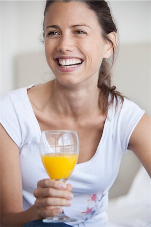 simsearch:632-07674617,k - Woman holding glass of juice, smiling cheerfully Stockbilder - Premium RF Lizenzfrei, Bildnummer: 632-07674615
