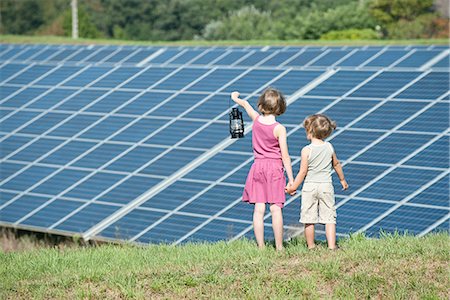 ecology - Children standing together in front of solar panels, girl holding old-fashioned latern Stock Photo - Premium Royalty-Free, Code: 632-07674620