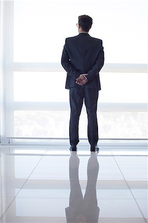 standing back - Businessman looking out high rise window at view of city below, rear view Stock Photo - Premium Royalty-Free, Code: 632-07674669