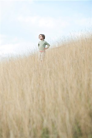 simsearch:633-05401482,k - Boy standing in tall grass, looking away in thought Photographie de stock - Premium Libres de Droits, Code: 632-07674677