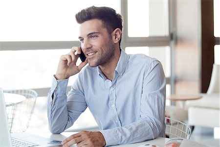 Man making cell phone call while using laptop computer Foto de stock - Sin royalties Premium, Código: 632-07674670