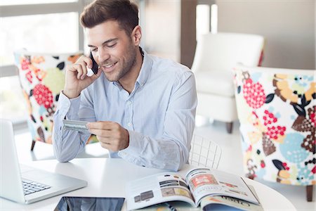 Man at home making credit card purchase over the phone Stock Photo - Premium Royalty-Free, Code: 632-07674672