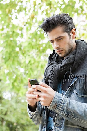 Young man using smartphone outdoors Stock Photo - Premium Royalty-Free, Code: 632-07809350