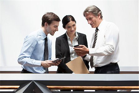 Businessman showing smartphone to colleagues Stock Photo - Premium Royalty-Free, Code: 632-07809469
