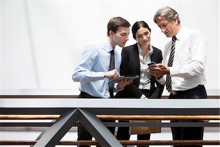 electronics smart phone tablet - Business colleagues looking at smartphone together Stock Photo - Premium Royalty-Free, Code: 632-07809470