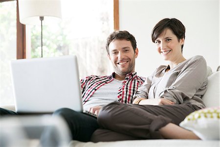 simsearch:632-07809512,k - Couple relaxing together on sofa with laptop computer Foto de stock - Royalty Free Premium, Número: 632-07809565