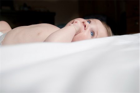 simsearch:632-06967589,k - Baby lying on back with finger in mouth Stock Photo - Premium Royalty-Free, Code: 632-07849554