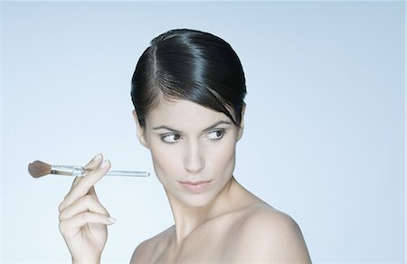 simsearch:614-00388878,k - Woman holding make-up brush, looking away Fotografie stock - Premium Royalty-Free, Codice: 632-07849556