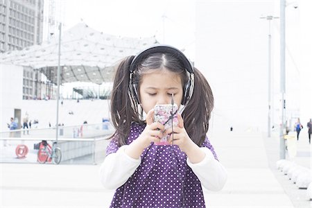 Girl looking at smartphone and listening to headphones outdoors Photographie de stock - Premium Libres de Droits, Code: 632-08001651