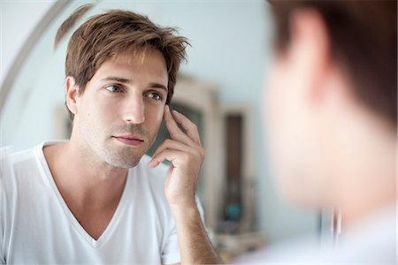 scrutinio - Man looking at self in mirror with concern about his complexion Fotografie stock - Premium Royalty-Free, Codice: 632-08001677