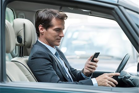 simsearch:632-08227418,k - Man looking at cell phone while driving Foto de stock - Sin royalties Premium, Código: 632-08001839