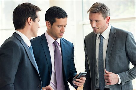 simsearch:6108-06166526,k - Businessman talking with colleagues, looking at smartphone Stock Photo - Premium Royalty-Free, Code: 632-08001850