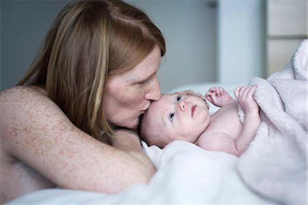 family laying in bed together - Mother kissing newborn baby Stock Photo - Premium Royalty-Free, Code: 632-08129915