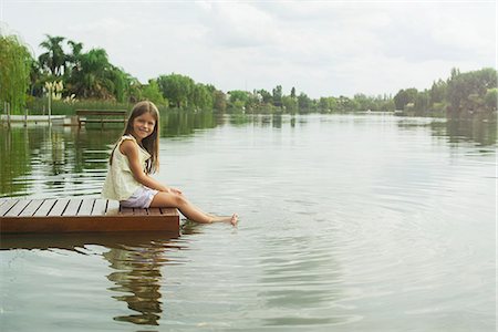 simsearch:632-08129951,k - Girl sitting on dock with feet dangling in lake, portrait Foto de stock - Sin royalties Premium, Código: 632-08129947