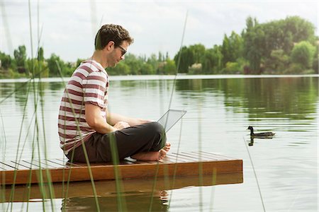 simsearch:632-03500777,k - Man sitting on dock using laptop computer Foto de stock - Royalty Free Premium, Número: 632-08129943