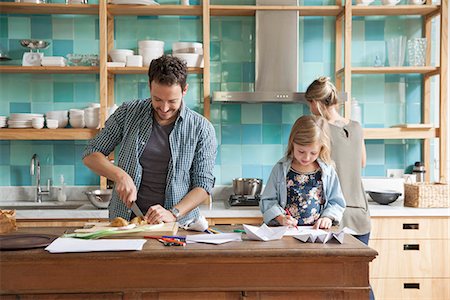 simsearch:632-07161504,k - Young daughter drawing ar kitchen counter while parents prepare meal Foto de stock - Sin royalties Premium, Código: 632-08227548