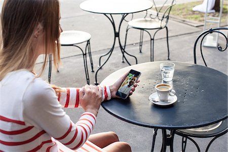 people sitting at a table - Young woman using multimedia smartphone in outdoor cafe Photographie de stock - Premium Libres de Droits, Code: 632-08331441