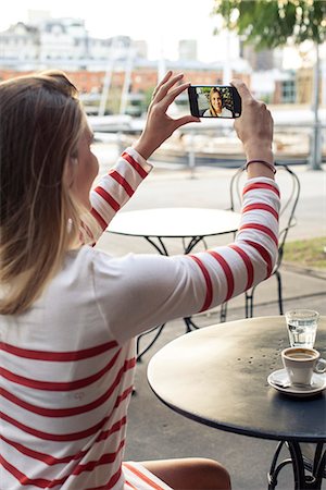 simsearch:633-08150929,k - Young woman taking a selfie at sidewalk cafe Foto de stock - Sin royalties Premium, Código: 632-08331443