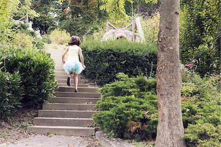 simsearch:632-03652319,k - Girl in tutu running up stairs in park, rear view Fotografie stock - Premium Royalty-Free, Codice: 632-08331456
