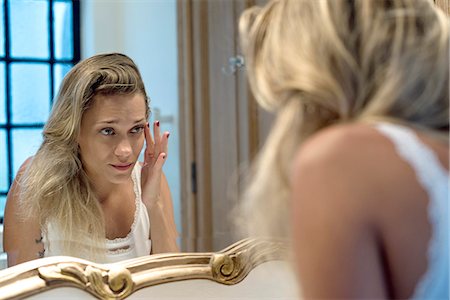 daily life - Woman looking bleary-eyed at self in bathroom mirror Photographie de stock - Premium Libres de Droits, Code: 632-08331542