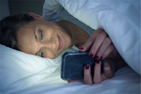 Woman lying in bed using smartphone Foto de stock - Sin royalties Premium, Código: 632-08331564