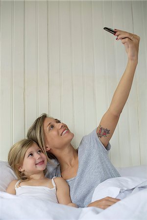 phone young woman bed - Mother and daughter posing for selfie Stock Photo - Premium Royalty-Free, Code: 632-08331601