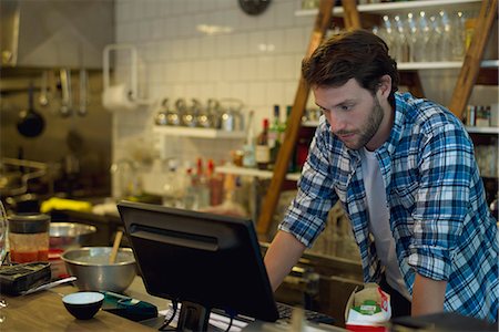 Cafe owner looking at cash register Stock Photo - Premium Royalty-Free, Code: 632-08331691