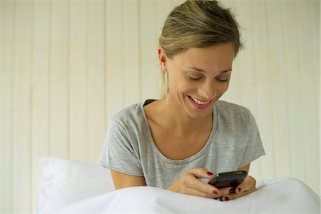 simsearch:6108-07969489,k - Woman sitting in bed texting Foto de stock - Sin royalties Premium, Código: 632-08331709