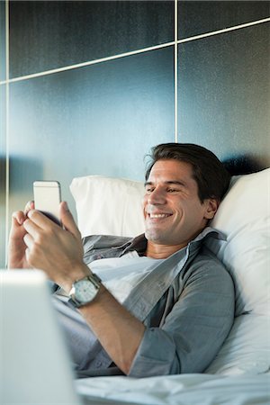 simsearch:632-07539911,k - Man relaxing in bed with multimedia smartphone Photographie de stock - Premium Libres de Droits, Code: 632-08545809