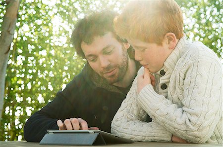 simsearch:632-08545827,k - Father and son looking at digital tablet together Fotografie stock - Premium Royalty-Free, Codice: 632-08545883