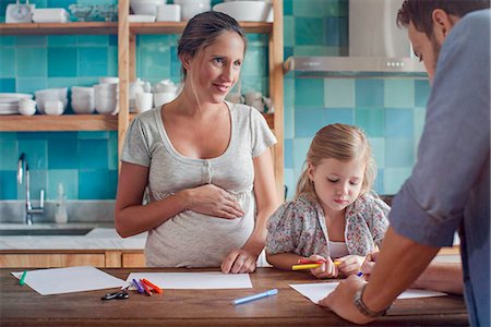 pregnant woman with daughter - Proud parents watch daughter color coloring book Stock Photo - Premium Royalty-Free, Code: 632-08545935