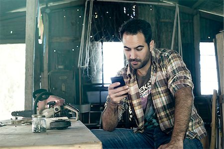 rustic workshop - Man browsing internet with smartphone during work break Stock Photo - Premium Royalty-Free, Code: 632-08698326